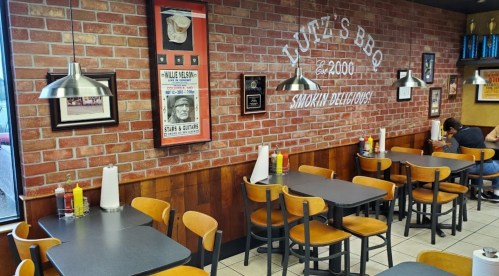 Interior of Lute's BBQ featuring brick walls, tables, and condiments, creating a cozy dining atmosphere.