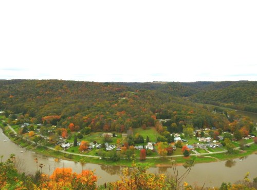 A scenic view of a river winding through colorful autumn foliage and small houses on the hillside.