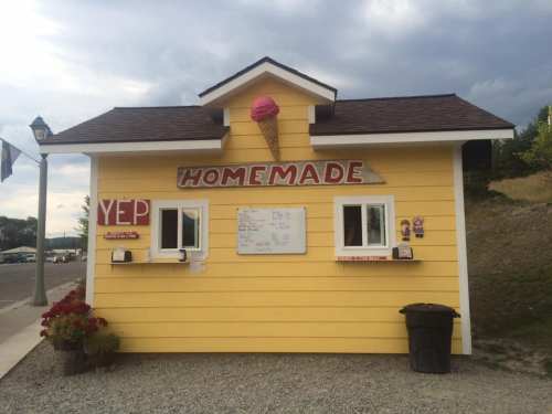 A small yellow ice cream stand with a sign reading "Homemade" and a pink ice cream cone on top.