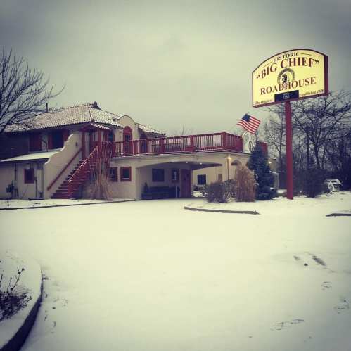 Historic Big Chief Roadhouse in winter, featuring a snow-covered entrance and a prominent sign.