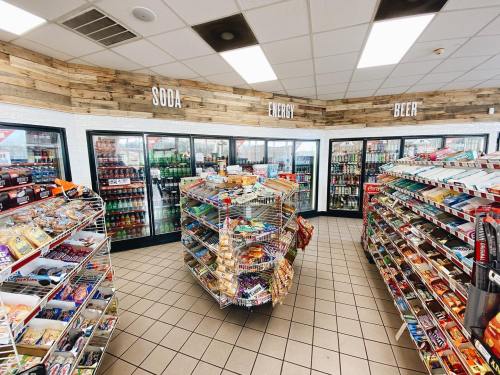 Interior of a convenience store with shelves of snacks and drinks, including soda, energy drinks, and beer.