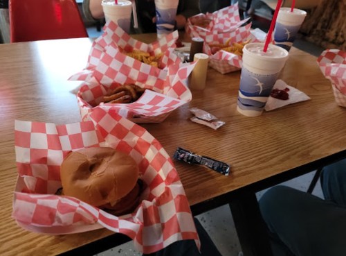 A table with red and white checkered baskets filled with burgers, fries, and drinks in a casual dining setting.