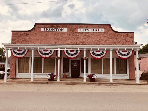 Historic Ironton City Hall adorned with red, white, and blue bunting, set against a cloudy sky.