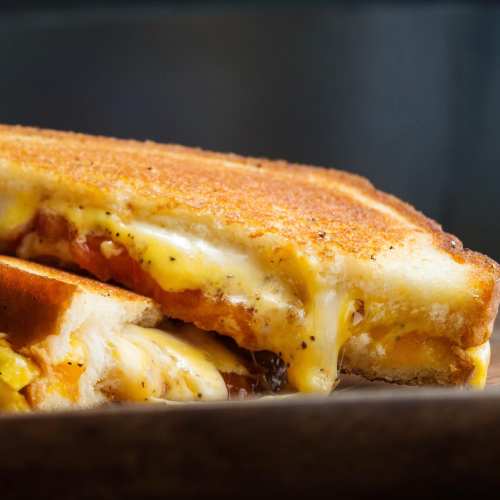 Close-up of a grilled cheese sandwich with melted cheese oozing from between two golden-brown slices of bread.