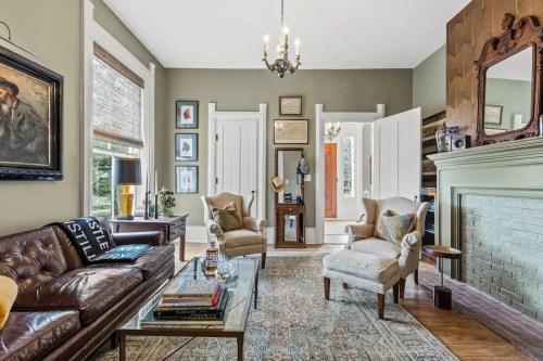 Cozy living room with a leather sofa, two armchairs, a glass coffee table, and decorative artwork on the walls.