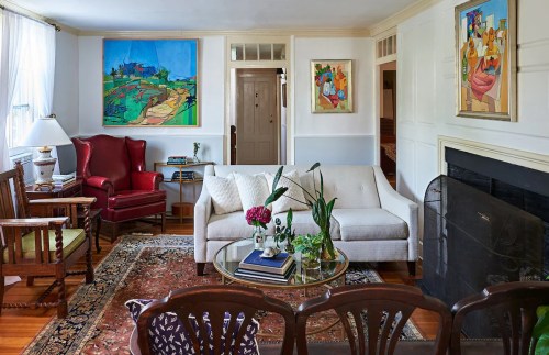 Cozy living room with a white sofa, colorful artwork, a coffee table with plants, and a warm, inviting atmosphere.