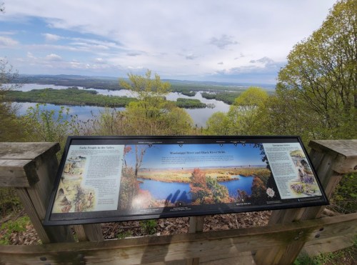 A scenic overlook featuring a sign with information about the Mississippi River and surrounding landscape.