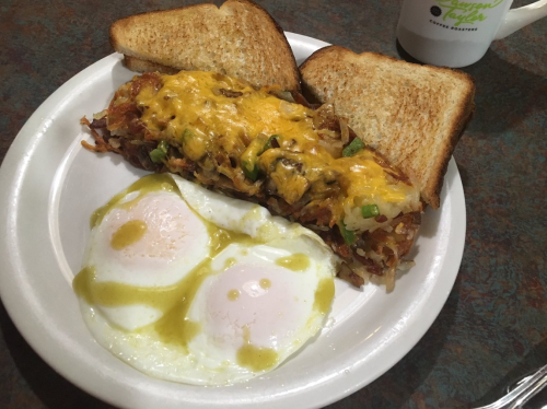 A plate with a cheesy hash brown casserole, two poached eggs, and two slices of toast.