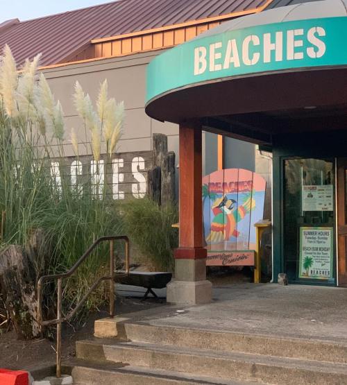Entrance to a beach-themed restaurant named "Beaches," featuring colorful signage and decorative plants.