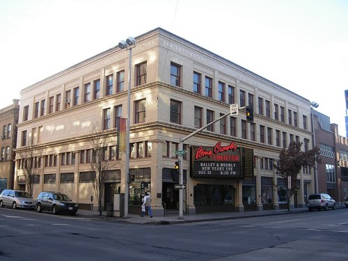 Historic theater building with a marquee, located at a street corner, featuring decorative architecture and large windows.