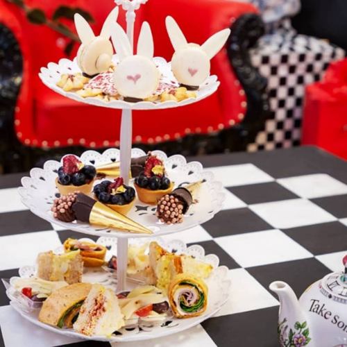 A tiered dessert stand with bunny-shaped treats, cupcakes, and savory snacks, set on a checkered table.