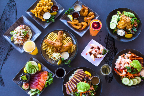 A vibrant spread of seafood dishes, including fried shrimp, fish, sushi, and colorful sides, arranged on stylish plates.