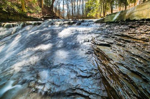 A serene waterfall cascading over rocky terrain, surrounded by lush trees in a tranquil forest setting.