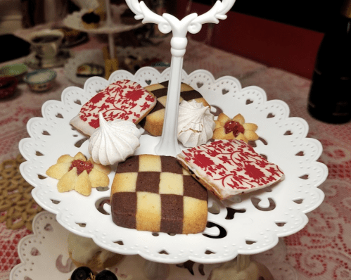 A tiered stand displaying an assortment of decorated cookies, including checkerboard, meringues, and floral designs.