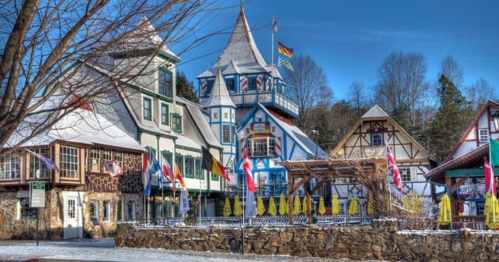 Charming alpine-style buildings with colorful flags and snow-covered ground in a picturesque village setting.