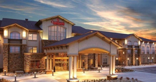 A modern hotel exterior at sunset, featuring stone accents and illuminated entrance.