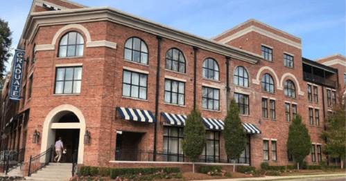 A brick building with large windows and striped awnings, featuring a sign that reads "Graduate."