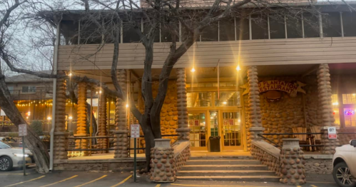 Exterior of a restaurant with stone pillars, warm lighting, and trees, creating a cozy atmosphere in the evening.
