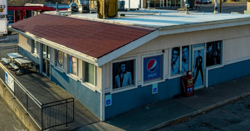 A building with a red roof and Pepsi signage, featuring large posters of various people on the walls.