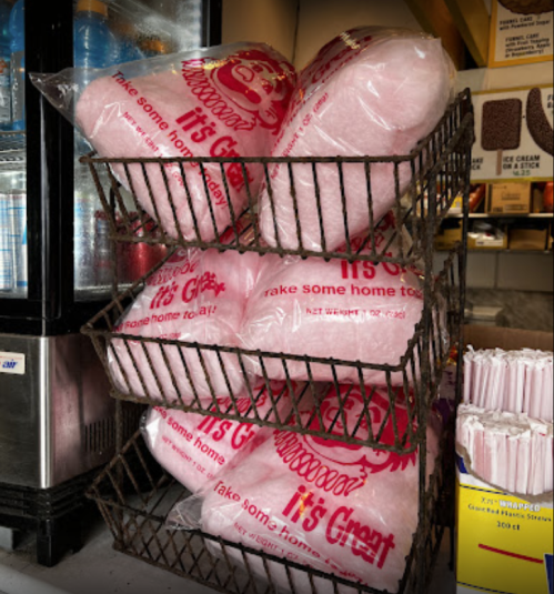 A wire basket filled with bags of pink cotton candy, labeled "It's Great! Take some home today!"