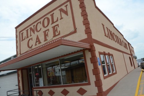 Exterior of Lincoln Cafe, featuring a large sign and a colorful storefront with windows.