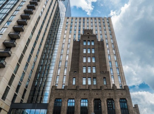 A mix of modern and historic buildings under a cloudy sky, showcasing contrasting architectural styles.