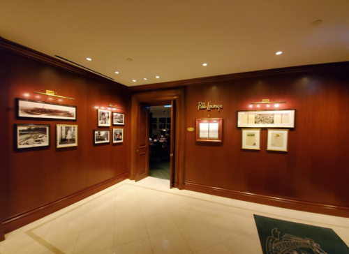 A warmly lit hallway with wooden walls, featuring framed photos and a sign for "Bla Lounge."