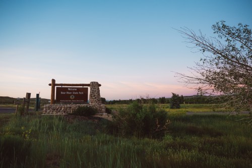 Welcome sign for Bear River State Park at dusk, surrounded by green grass and a clear sky.
