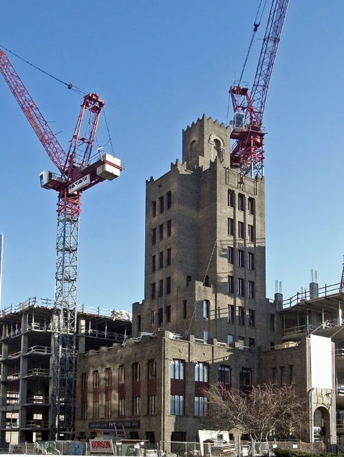 Historic building under construction with cranes, showcasing a blend of old architecture and modern development.