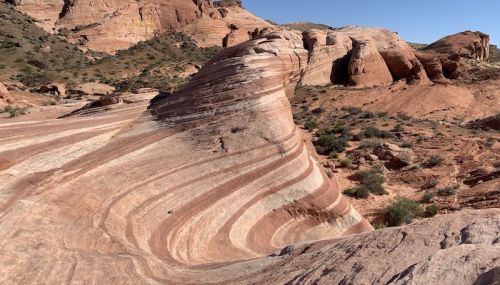 Colorful, layered rock formations in a desert landscape under a clear blue sky.
