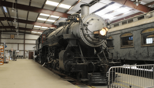 A vintage steam locomotive displayed indoors, showcasing its black exterior and classic design.