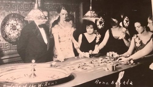 A vintage black-and-white photo of people at a casino table in Reno, Nevada, dressed in formal attire.