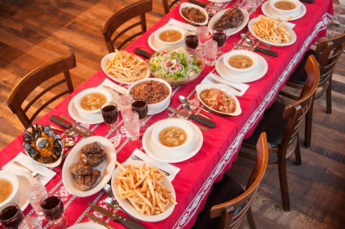 A beautifully set dining table with various dishes, including salads, soups, fries, and drinks, ready for a meal.