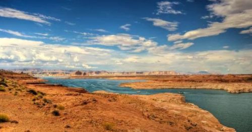 A scenic view of a river winding through rocky terrain under a blue sky with scattered clouds.