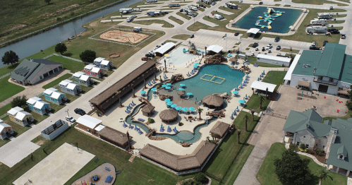 Aerial view of a resort-style pool area with cabanas, surrounded by RVs and recreational facilities.