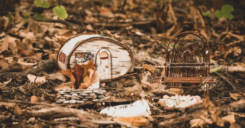 A whimsical scene in the forest featuring a small wooden cabin, a woven chair, and decorative natural elements.