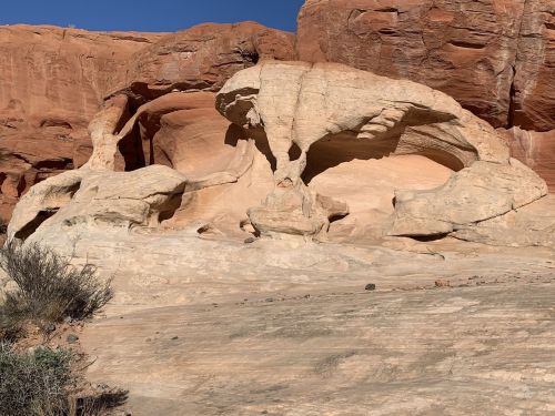 A unique rock formation with smooth, curved shapes and natural arches, set against a clear blue sky.