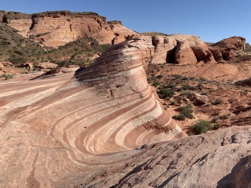 Colorful, layered rock formations in a desert landscape under a clear blue sky.