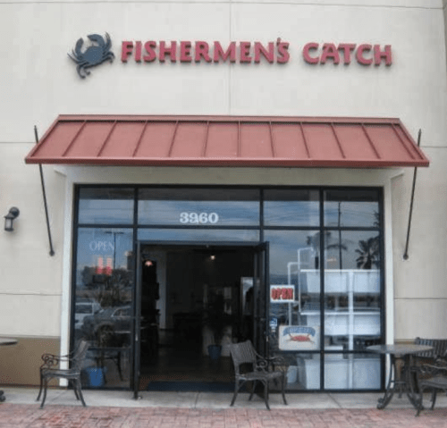 Exterior of "Fishermen's Catch" restaurant with a red awning and open sign, featuring outdoor seating.