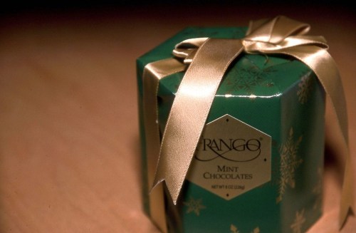 A green hexagonal gift box tied with a gold ribbon, labeled "Mint Chocolates."