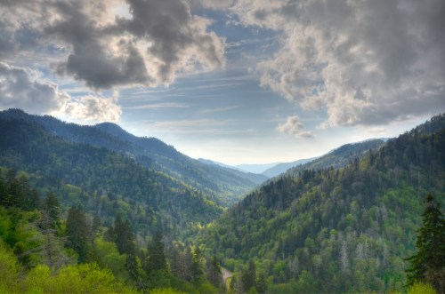 A scenic view of lush green mountains under a cloudy sky, with valleys stretching into the distance.