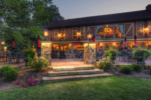 A charming outdoor patio with stone steps, lanterns, and vibrant flowers, leading to a cozy lodge at dusk.