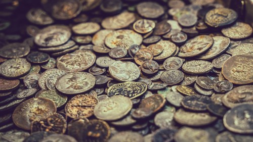 A close-up of a scattered collection of various ancient coins, showcasing intricate designs and details.