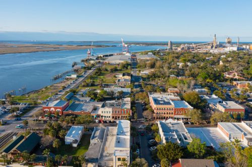 Aerial view of a coastal town with a river, industrial area, and historic buildings along the waterfront.