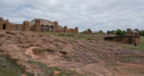 A rocky landscape featuring stone structures and ruins under a cloudy sky.