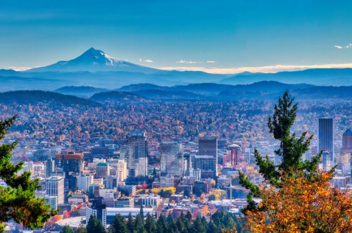 A panoramic view of Portland, Oregon, with Mount Hood in the background and colorful autumn foliage in the foreground.