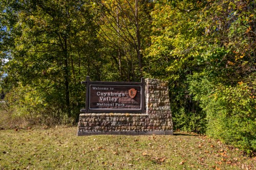 Sign welcoming visitors to Cuyahoga Valley National Park, surrounded by lush green trees and autumn foliage.