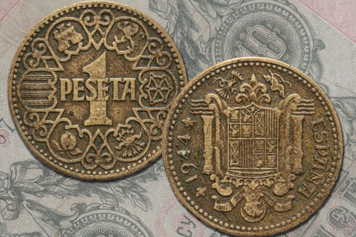 A 1 peseta coin from 1944, featuring intricate designs on both sides, set against a background of banknotes.