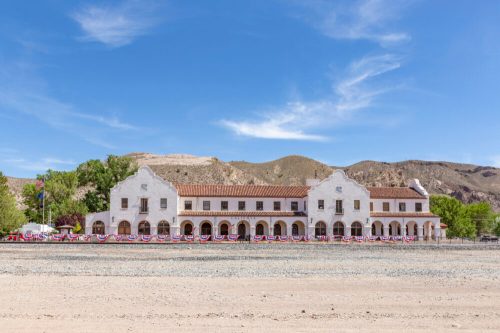 Historic building with a white facade, red tile roof, and patriotic bunting, set against a mountainous landscape.