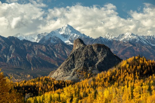 A stunning mountain landscape featuring snow-capped peaks and vibrant autumn foliage in the foreground.